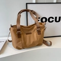 Borsa tote in nylon caramello con doppi manici e tracolla in un contesto minimalista - Marrone