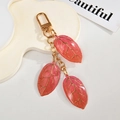 Pink resin leaf keychain with gold veins and glitter sequins on a white display board - Red-Pink Gradient
