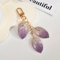 Macro detail of purple gradient resin leaf charms with gold metal veins on keychain - Purple White Gradient