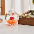 Close-up of heart-shaped acrylic keychain with red rose and flowing orange quicksand - Light Gold Chain + Rose Heart Lock / Orange