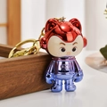 Close-up of metallic gradient astronaut keychain with red helmet and LUCK engraving - Fuschia