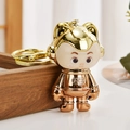 Detail of a golden electroplated astronaut keychain with Luck lettering on the chest - Golden Orange