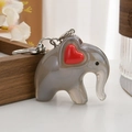 Close-up of a translucent gray elephant keychain with a red heart and silver metal clasp - Black