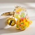 Macro shot of liquid unicorn keychain with colorful beads and golden bell on acrylic shell - Yellow Unicorn