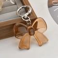 Amber acrylic bow keychain with silver metal ring clasp on a minimalist display - Orange