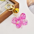 Dettaglio portachiavi a farfalla rosa con glitter liquidi e campanellino dorato lucido - Viola Luminoso