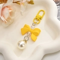 Detail of yellow bow keychain with large pearl pendant and colorful beads on tray - Lemon Yellow