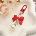 Detail of red bow keychain with pearl and translucent beads on a white cloud tray - Red
