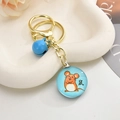 Detail of golden zodiac keychain with blue bell and cartoon mouse pendant on white stone - Blue Mouse / Light Gold Chain + Small Gemstones + Bell