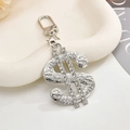 Close-up of sparkling silver dollar sign charm with micro-pave crystals on ceramic tray - Keychain + Pendant / Dollar