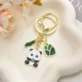 Portachiavi panda e bambù in metallo dorato su un vassoio decorativo bianco - Panda che Mangia Germogli di Bambù