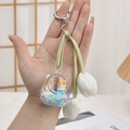 Cute liquid bear keychain with white tulips and green ribbon held in hand - School Bag