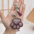 Handheld view of purple rhinestone bear paw keychain with matching tassel and silver bell - Tassel Style / Purple