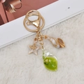 Detail of nautical keychain with starfish and resin conch shells on white rug background - Green