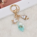 Ocean theme keychain with starfish and conch shell charms on a white plush rug - Blue
