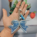 Hemelblauwe strik sleutelhanger met strassteentjes, leren kwastje en zilveren belletje - Blauw