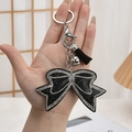 Chic black rhinestone bow keychain with silver bell and tassel detail - Black with White Edge