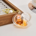 Detail of heart acrylic keychain with orange liquid sand, bunny doll and pearl charm - Light Gold Chain + Heart + Pearl / Orange