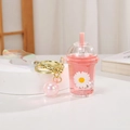 Pink glowing bubble tea cup keychain with drifting sand and white daisy floral print - Daisy Quicksand Glowing Milk Tea Cup / Pink