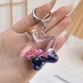 Detail eines sternförmigen Treibsand-Schlüsselanhängers mit rosa Muscheln und Pailletten - Silberner Ring Lila