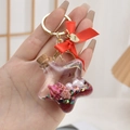 Sternförmiger Acryl-Schlüsselanhänger mit Treibsand, rosa Muscheln und roter Schleife - Satin-Schleife Rot