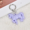 Vista dettagliata di un portachiavi a cavallo in acrilico viola con chiusura in argento su pelliccia - Pony / Viola