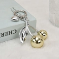Gold cherry fruit keychain with silver heart pendant and metallic leaves on velvet - Gold