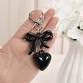 Portachiavi con fiocco nero lucido, ciondolo a cuore e anello d'argento in mano - Anello Argento + Cuore + Fiocco / Nero