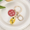 Gouden sleutelhanger met Peace and Joy hanger en goudstaaf op een wit keramiek bord - Vrede en Vreugde