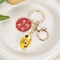 Gouden sleutelhanger met Good Luck hanger en goudstaaf op wit keramieken dienblad - Veel Geluk