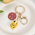 Detail of red enamel pendant with gold ingot charm on a lucky metal keychain - Happiness Upon Going Out