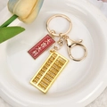 Goldener Abakus Schlüsselanhänger mit Da Ji Da Li Anhänger auf weißem Keramikteller - Viel Glück und Wohlstand (Goldverschluss + Abakus)
