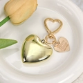 Dettaglio del ciondolo a cuore dorato lucido con etichetta incisa su piatto bianco - Cuore a Specchio Oro con Targhetta