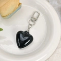 Close-up of a glossy black heart charm with a silver lobster clasp on a white plate - Black High Gloss Heart Charm