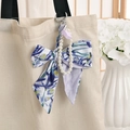 Floral bow phone charm with pearl strap on a canvas bag for elegant accessory styling - Purple