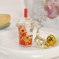 Detail of Capybara liquid keychain with red fluid, stars, and golden bell charm - Red Milk Cap