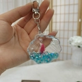 Detail of shell-shaped acrylic keychain with blue star glitter and pink dolphin charm - Shell Shape - Gate Buckle Style
