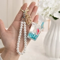 Macro view of blue liquid ocean bottle keychain with dolphin and white pearl strap - Milk Tea Cup Shape - Pearl Chain & Buckle Style