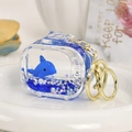 Llavero de delfín azul con líquido y purpurina sobre un plato decorativo de porcelana - Ballena Azul Real