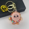Detail view of round orange liquid shaker keychain with glitter and cute cartoon face - Light Gold Clasp+Bell+Eggy(654856) / Sparkling Orange