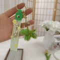 Close-up of green floral liquid sand keychain with Happy Moments silicone hand strap - Green Starfish