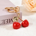 Detailed close-up of red cherry charms with gold hardware on a soft pastel background - Smooth Lighter Buckle - Glossy Resin