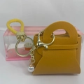 Detail der ingwergelben PU-Leder Mini-Münztasche mit Perlenanhänger und goldener Klammer - Ingwergelb