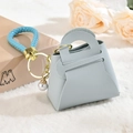 Mini monedero de cuero sintético con correa trenzada azul y perla sobre piel sintética blanca - Azul Niebla