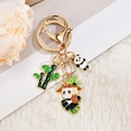 Detaillierte Nahaufnahme eines goldenen Panda-Schlüsselanhängers mit Bambus und Sake-Krug-Anhängern - Panda mit Wein