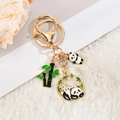 Vue détaillée d'un porte-clés panda chinois avec pendentifs dorés et bambou vert émaillé - Panda Penché