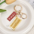 Macro shot of golden metal abacus and red lucky tag keychain on white porcelain plate - Lucky Orange