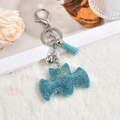 Detail of bat-shaped rhinestone keychain with blue tassels and silver bell on plush - Tassel Blue