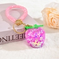 Vue détaillée du pendentif fraise violette avec dragonne rose pailletée sur fausse fourrure - Style Dragonne en Strass Violet