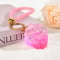 Porte-clés fraise en résine rose avec paillettes et dragonne tissée sur fond en peluche - Style Dragonne en Strass Rose